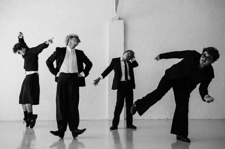 Australian indie band The Rions posing dynamically in black-and-white suits against a white studio background.